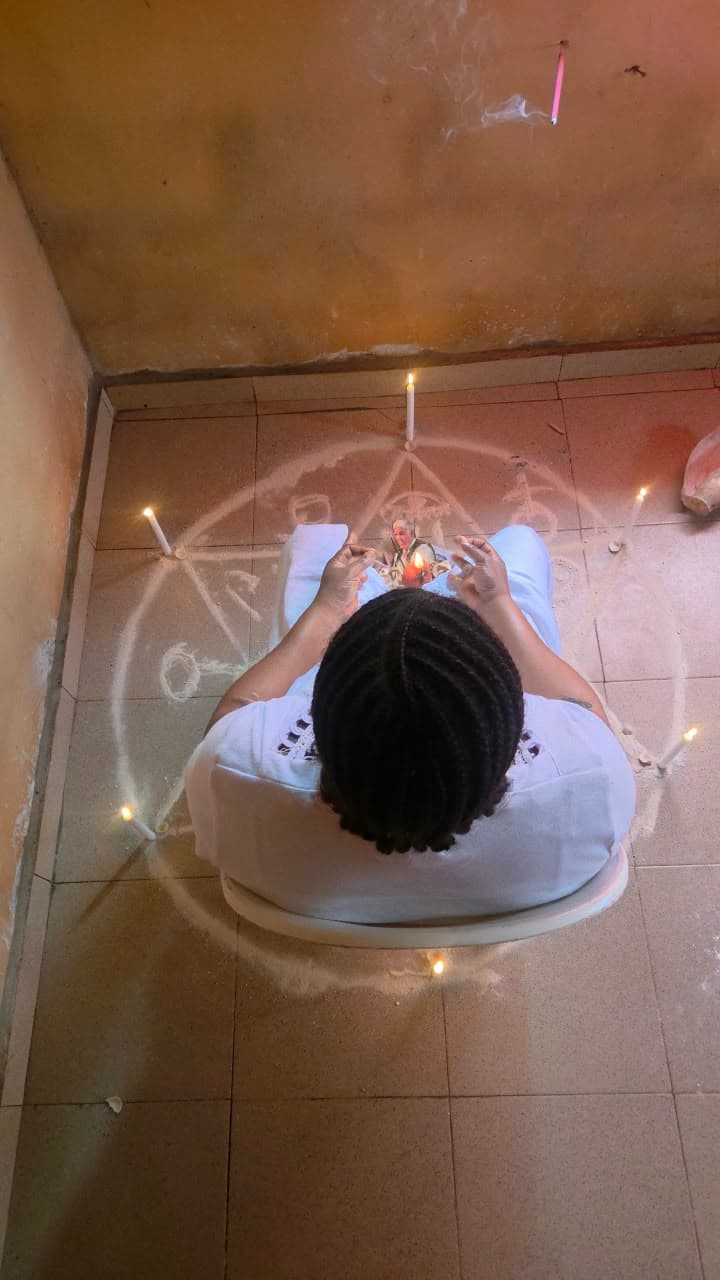 A practitioner seated in a chalk circle surrounded by white candles